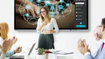 Office workers clapping in meeting room with a presentation on screen and a printer at the side