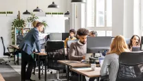 Office workers working at desk and an informal meeting