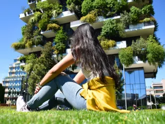 A girl sat in front of a building with plants
