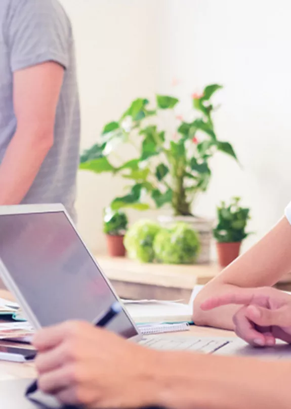 Two young colleagues seated and collaborating in the foreground and two colleagues standing and collaborating in the background